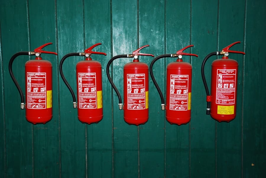 Five red fire extinguishers mounted in a row on a green wooden wall.