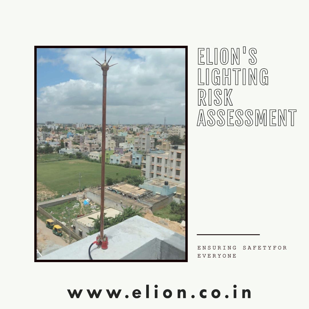 A lightning rod is installed on a rooftop overlooking a cityscape with buildings and greenery under a cloudy sky. Text reads Elions Lighting Risk Assessment and Lightning Arrester for ensuring safety for everyone. Website: www.elion.co.in.
