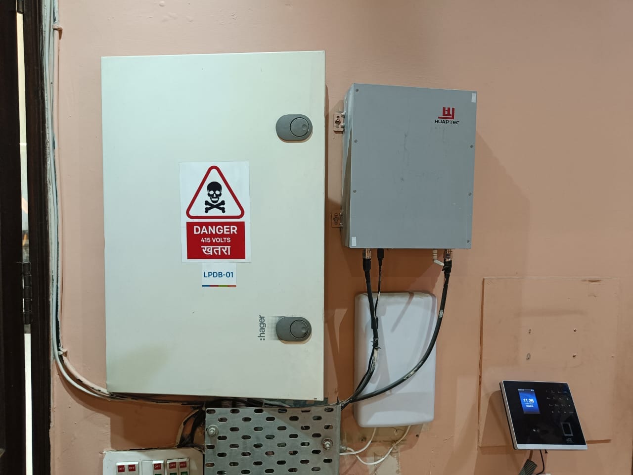 A wall-mounted electrical panel with a Danger 415 Volts warning sign, a smaller grey box, cables, and an access control device below—ideal for inclusion in any thorough fire safety inspection.