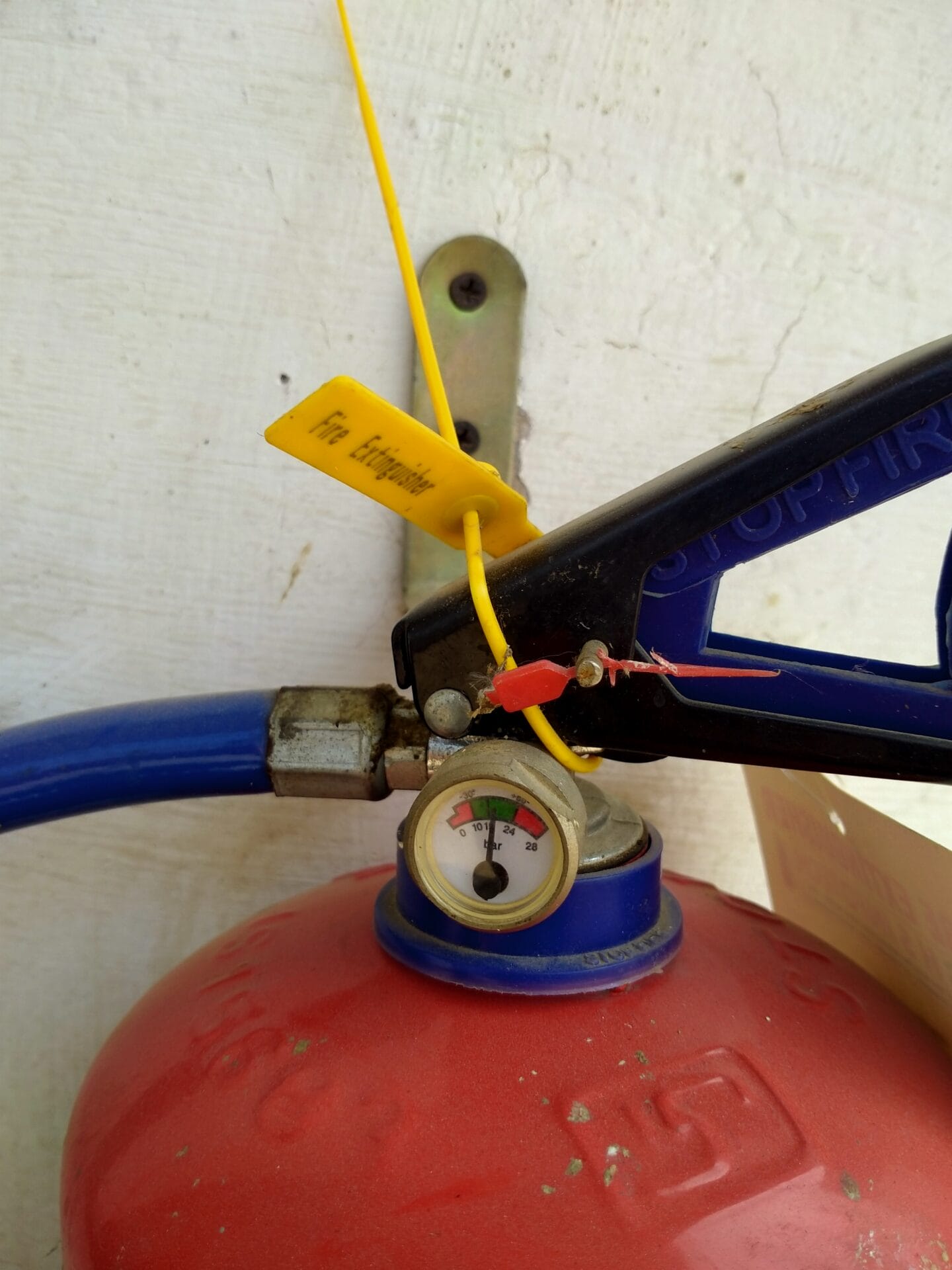 Close-up of a red fire extinguisher with a yellow safety seal labeled Fire Extinguisher and a pressure gauge in the green, reflecting equipment reliability and supporting essential fire safety in any environment.