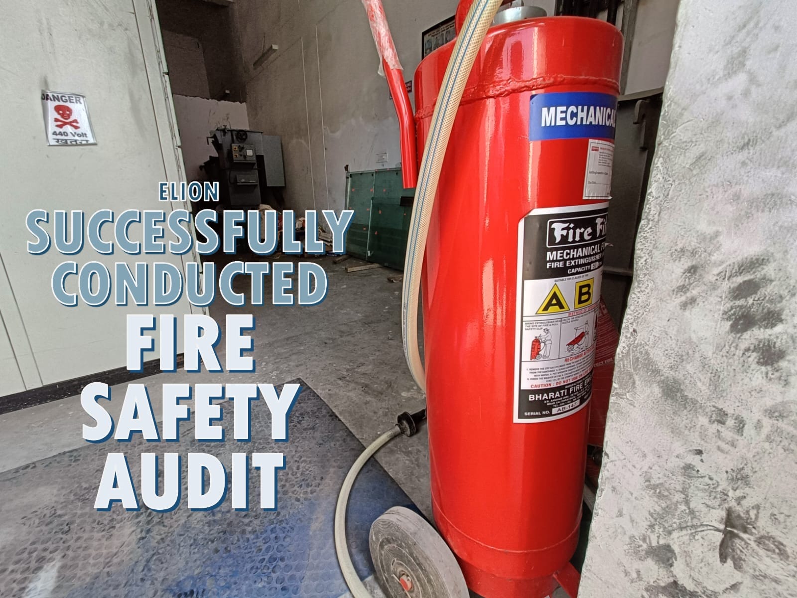 A large red fire extinguisher stands in an industrial setting. Overlaid text reads, Elion successfully conducted a fire safety audit. Equipment and a warning sign are visible in the background, highlighting the importance of a thorough fire safety inspection.