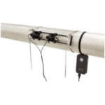 A black electronic sensor device is attached to a large horizontal metal pipe with straps and chains, with wires connected between the device and the pipe.