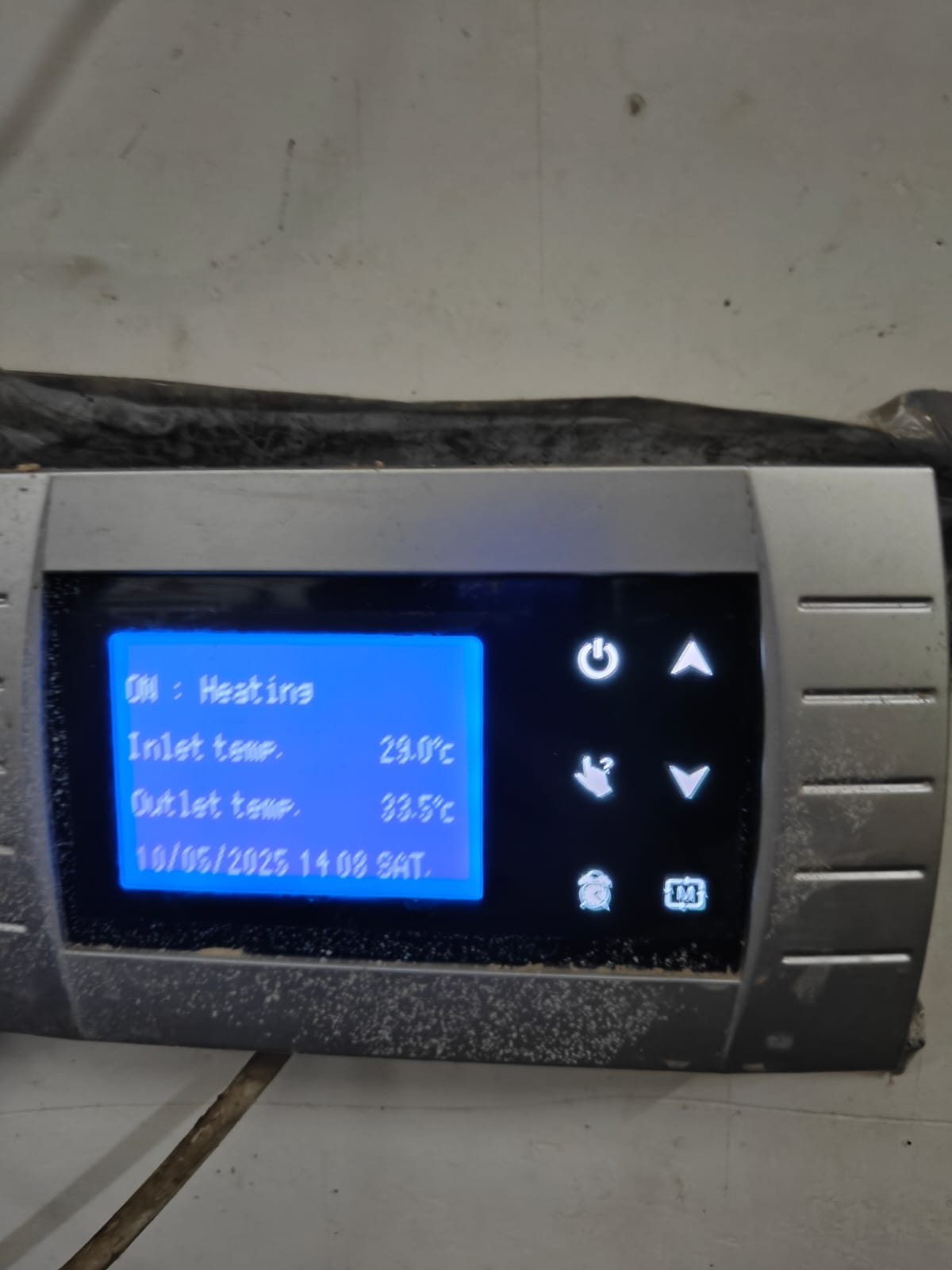 A digital control panel, used for food industry safety, displays ON: Heating, an inlet temperature of 29.0°C, an outlet temperature of 33.5°C, and the date and time as 10/05/2023 14:08 SAT. The panel is installed on a wall.