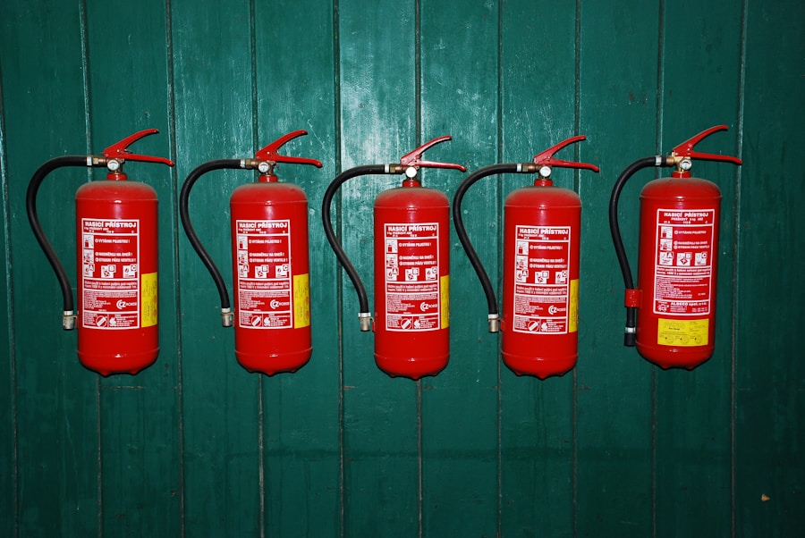 Five red fire extinguishers are mounted in a row on a dark green wooden wall, each labeled with safety instructions and black hoses attached.